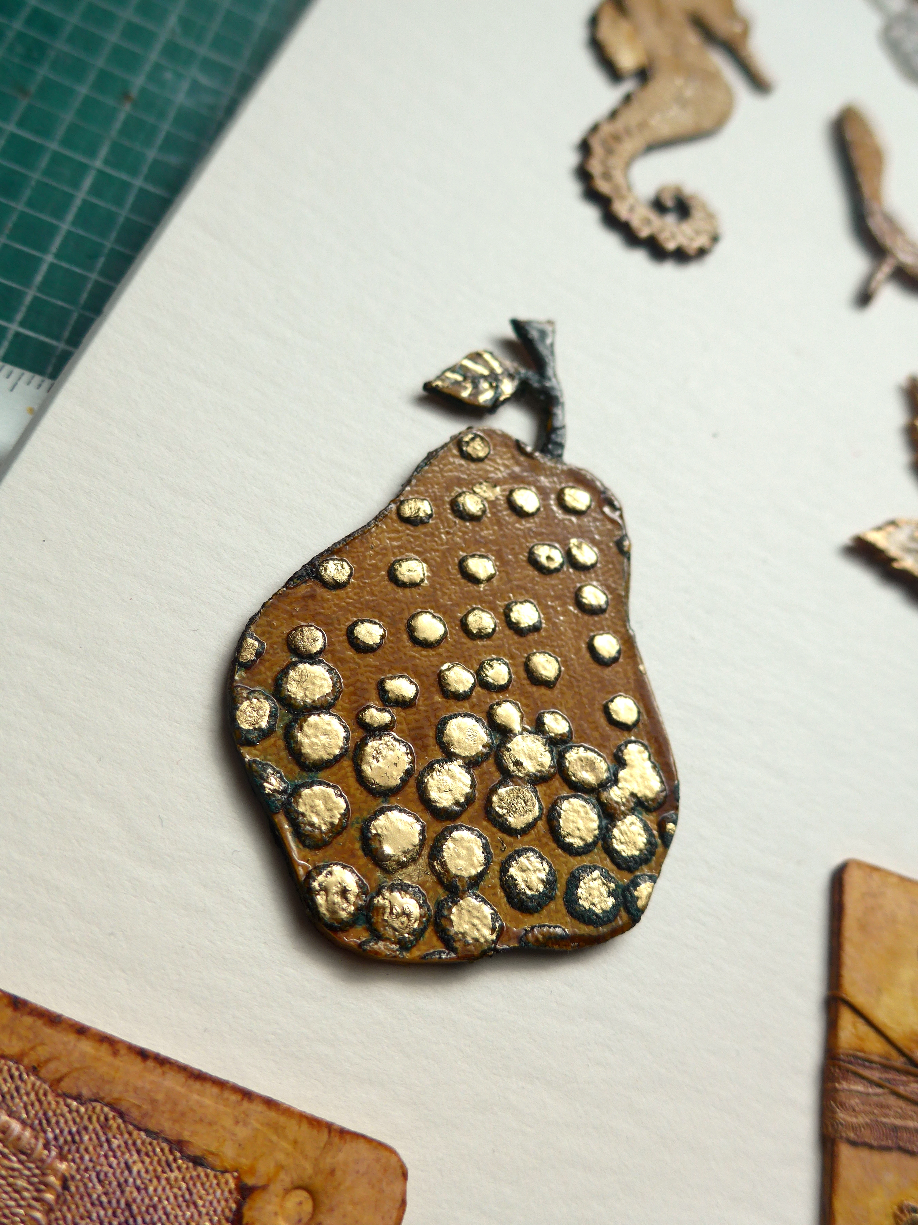 Collagraph plate of a pear decorated with gold paint